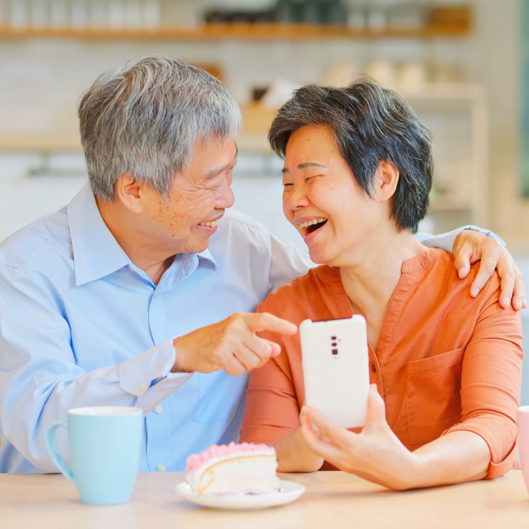 Asian couple looking at phone and laughing